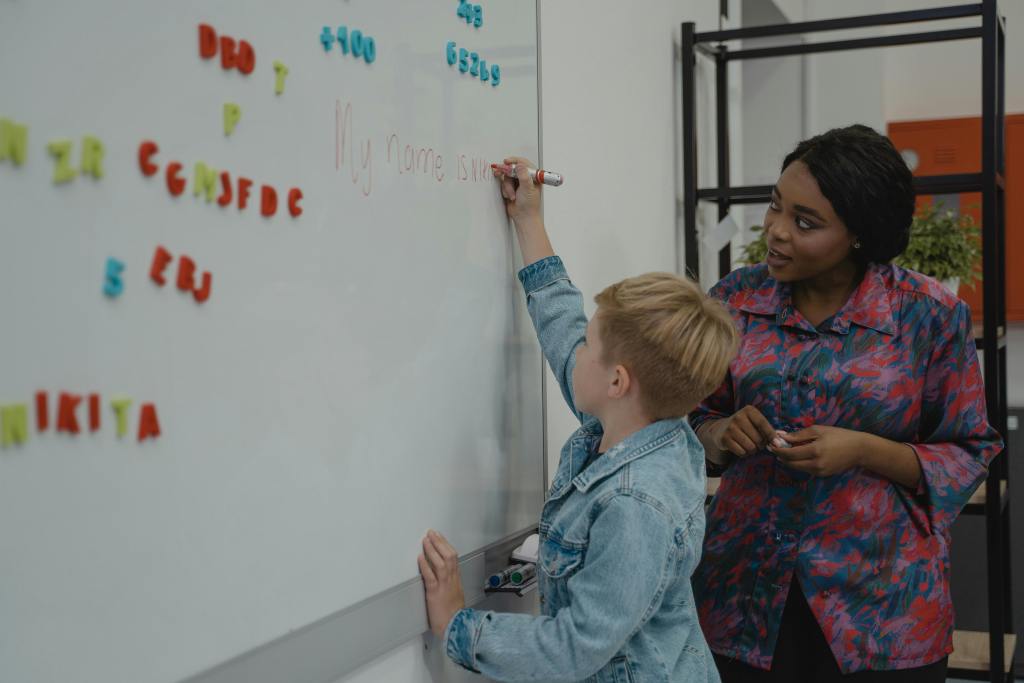 A teacher helping a student write on a whiteboard.